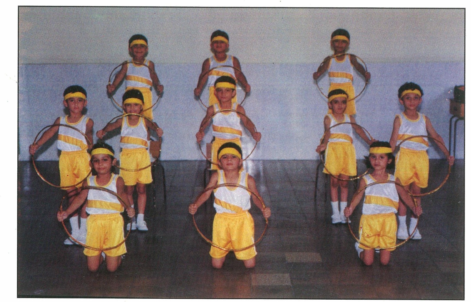 Children in yellow costumes holding hoops for a performance